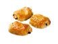 Trois pains au chocolat dorés sur fond noir.