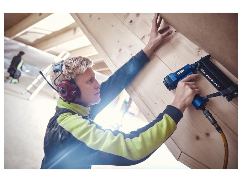 Homme utilisant une agrafeuse/cloueuse pneumatique LIVARNO® pour fixer des panneaux en bois.