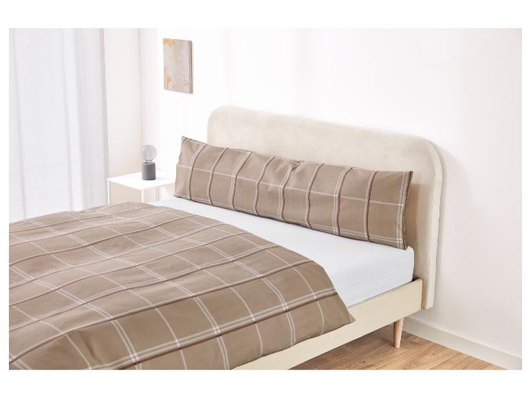 Lit avec une tête de lit beige et une housse de couette et taie d'oreiller à carreaux.