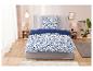 Parure de lit fleurie bleu marine et blanche sur lit gris.