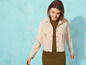 Une femme portant une veste beige et une robe verte.