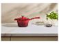Casserole rouge avec couvercle sur un comptoir en marbre blanc, avec une plante et des épices.