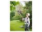 Femme coupant des branches dans un jardin avec un sécateur télescopique.