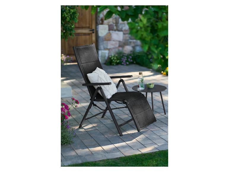 Transat de jardin noir avec coussin et table basse sur une terrasse.