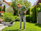 Un homme utilise une débroussailleuse dans le jardin.