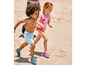 Deux enfants courent sur la plage, l'un porte un short de bain bleu et l'autre un maillot de bain rose à motif de flamant rose.