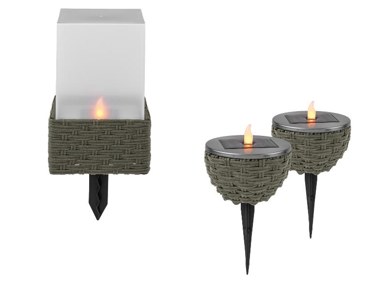 Luminaires solaires de jardin : une lanterne carrée et deux torches rondes avec des flammes vacillantes.