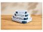 Ensemble de quatre récipients de conservation alimentaire pliables bleus et blancs, empilés sur une table en bois.