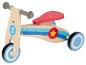 Un vélo d'équilibre en bois pour enfant avec des roues bleues et une selle rouge.