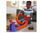 Enfant jouant avec le coffret de jeu Hot Wheels Monster Trucks sur le sol.