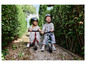 Deux enfants sur des draisiennes Hudora sur un chemin de jardin.