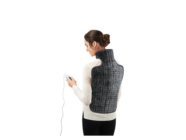 Femme portant un coussin chauffant électrique pour le dos et le cou, tenant la télécommande.