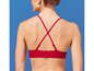 Une femme porte un haut de bikini rouge avec des bretelles croisées.