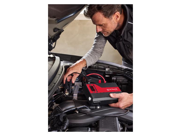 Homme utilisant un démarreur de batterie Ultimate Speed sur une voiture.