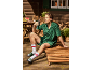 Homme en ensemble de salon vert et claquettes avec chaussettes, buvant d'une bouteille d'eau à l'extérieur.