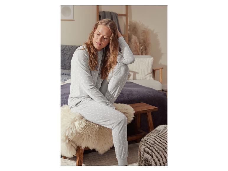 Une femme porte un pyjama gris à pois blancs.