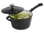 Casserole en fonte noire avec couvercle, remplie de soupe verte et d'herbes
