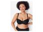 Une femme présente un soutien-gorge noir à dentelle et des sous-vêtements taille haute assortis.
