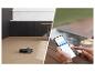 Robot aspirateur nettoyant un sol en bois, contrôlé par un smartphone.