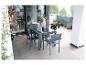 Ensemble repas extérieur gris avec quatre chaises et table en verre sur un balcon.