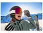 Une femme souriante portant un casque de ski CRIVIT et un masque de ski photochromique premium.
