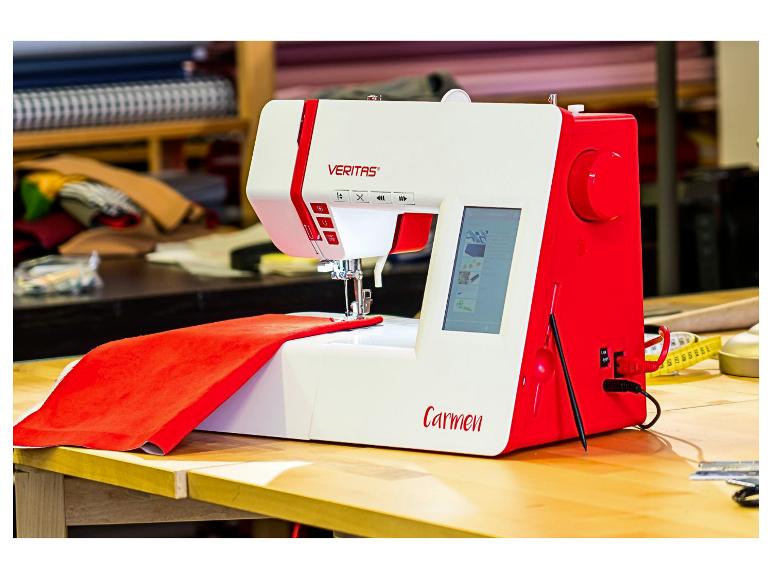 Machine à coudre rouge et blanche avec tissu sur une table en bois dans un atelier