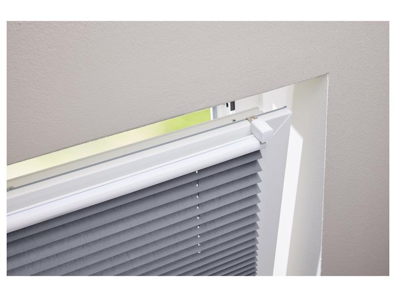 Stores plissées grises installées sur une fenêtre de toit.