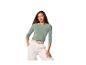 Femme portant un haut vert à manches longues et un pantalon blanc avec une ceinture tressée.