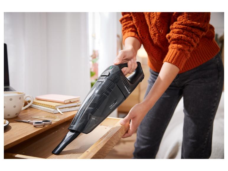 Une personne nettoie un tiroir avec un aspirateur sans fil Silvercrest.