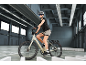 Femme à vélo électrique avec casque et lunettes de soleil dans un garage.