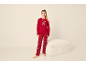 Fille en pyjama de Noël rouge avec motif d'ours en peluche, debout à côté d'un pouf blanc