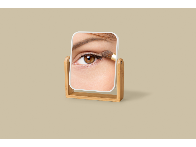 Miroir avec un œil de femme appliquant du fard à paupières