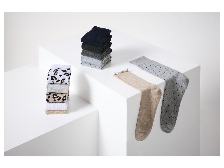 Chaussettes pliées et empilées, y compris des motifs à pois et léopard, sur une surface blanche.
