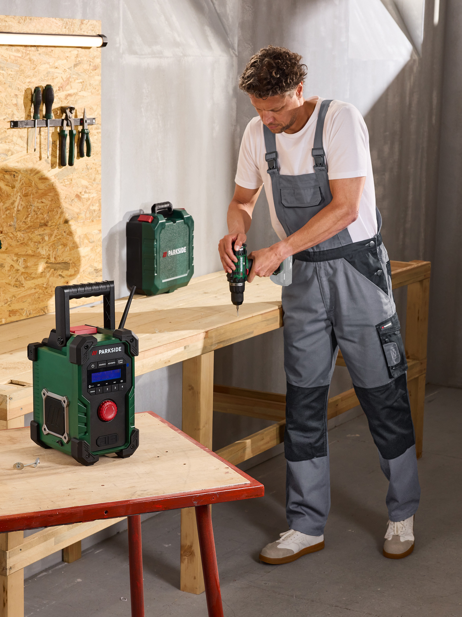 Homme perçant du bois, avec une radio et une boîte à outils à proximité dans un atelier.
