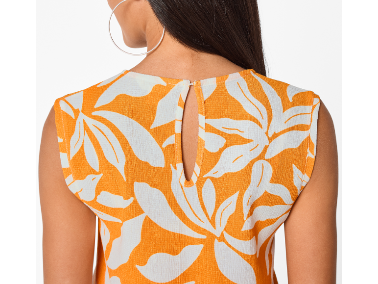 Dos d'une femme portant un haut orange à motifs floraux blancs avec une découpe.