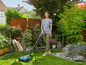 Une femme avec un robot tondeuse dans un jardin.
