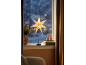 Étoile de Noël lumineuse sur pied posée sur le rebord de la fenêtre.