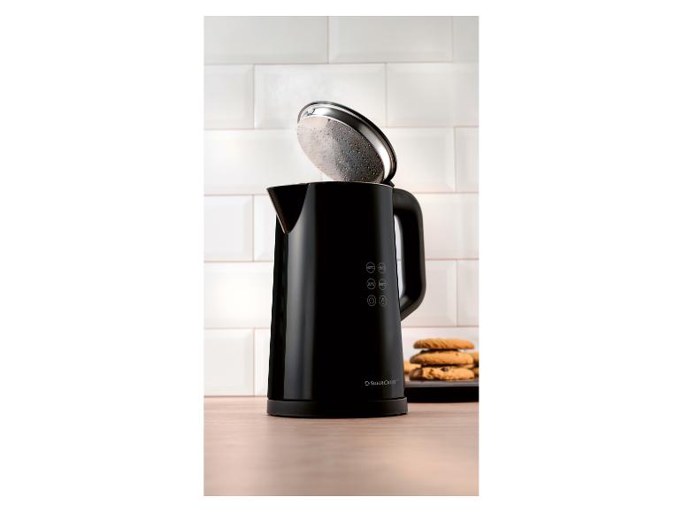 Bouilloire noire avec couvercle ouvert et biscuits sur une table en bois.