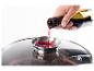 Du vin rouge versé dans un couvercle en verre avec un rebord métallique, recouvrant une marmite de nourriture.