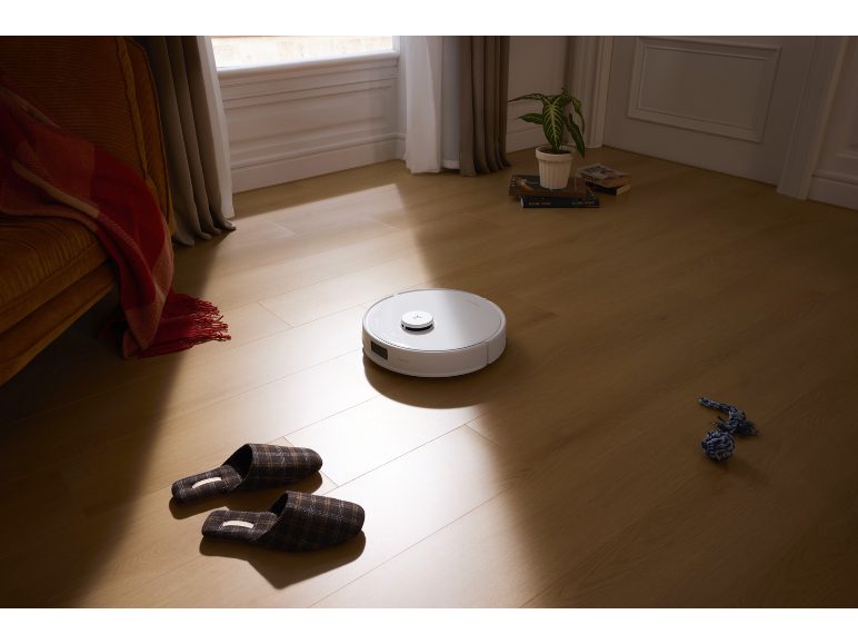 Aspirateur robot blanc sur un parquet dans un salon.
