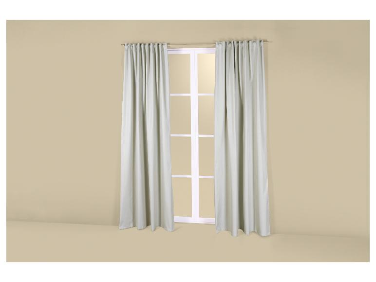 Une fenêtre avec des rideaux gris clair dans une pièce aux murs beiges.
