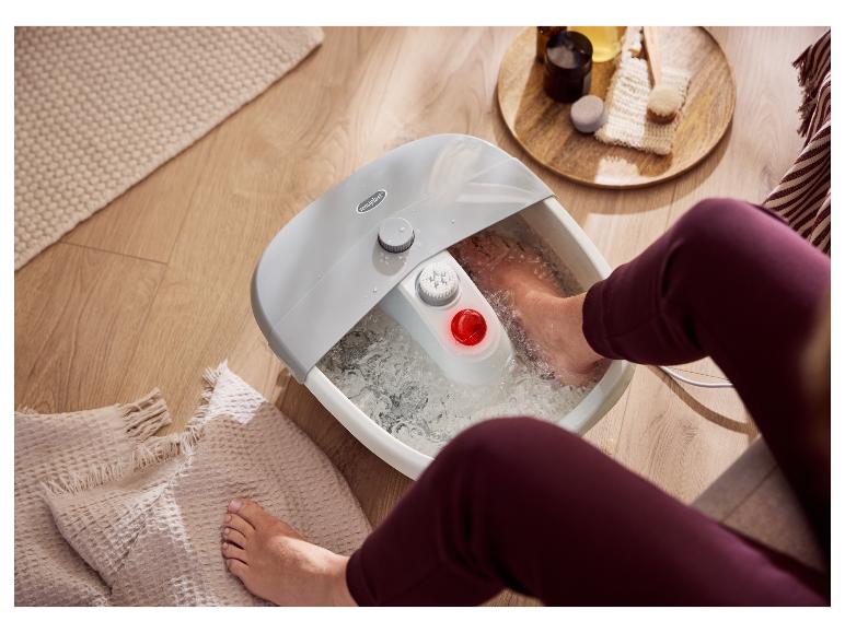 Une personne se relaxe les pieds dans un bain de pieds Sensoplast.