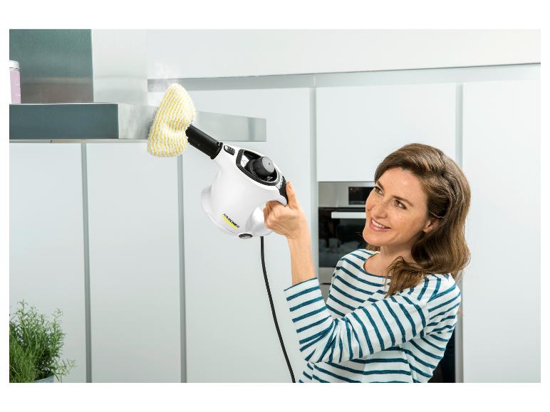 Femme nettoyant une hotte de cuisine avec un nettoyeur vapeur à main, souriante.