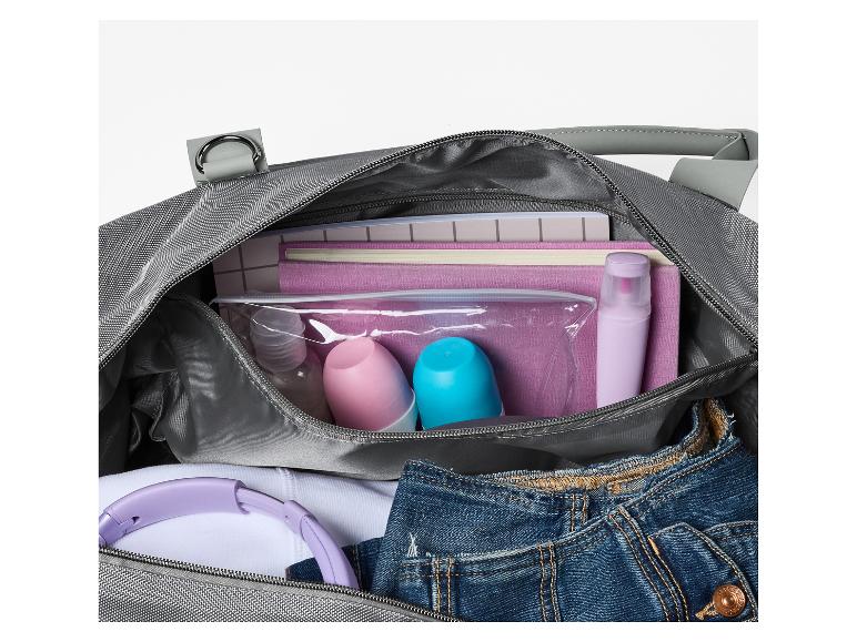 Sac de voyage gris clair avec articles de toilette, écouteurs et jean.