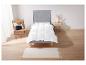 Une couette blanche sur un cadre de lit gris avec un tapis et une chaise.