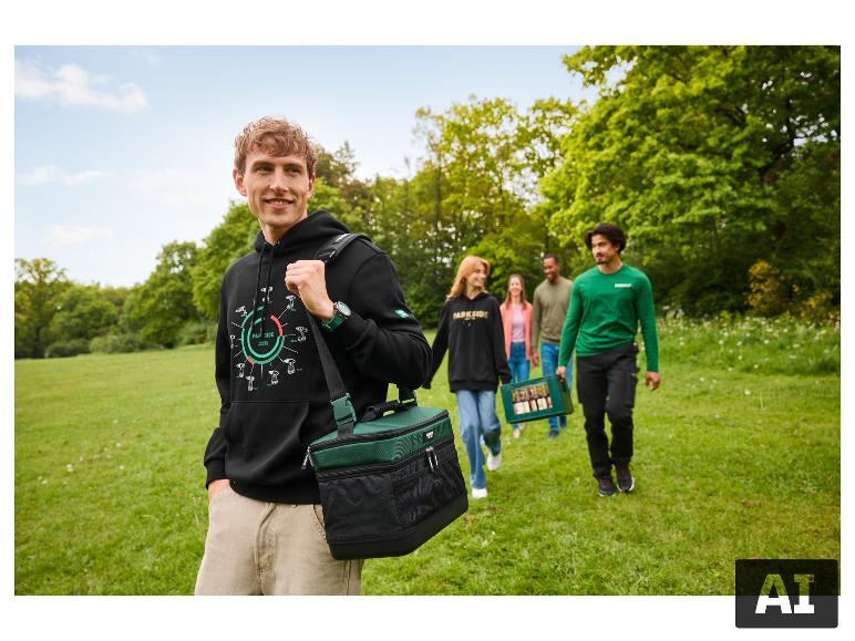 Homme en sweat à capuche noir avec sac isotherme vert, marchant avec des amis dans un parc.