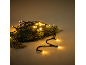 Guirlande lumineuse LED blanc chaud entrelacée avec des branches de pin vert.