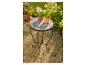 Petite table d'extérieur en métal noir avec plateau mosaïque et pots de fleurs.