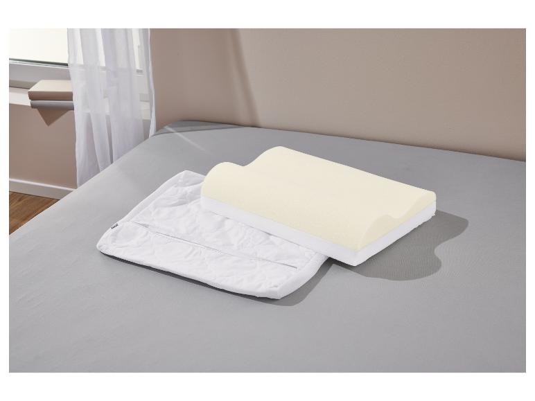 Un oreiller en mousse à mémoire de forme et sa taie d'oreiller sont posés sur un lit.