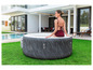 Une femme en maillot de bain se détend dans un jacuzzi gonflable Lay-Z-Spa dans le jardin.